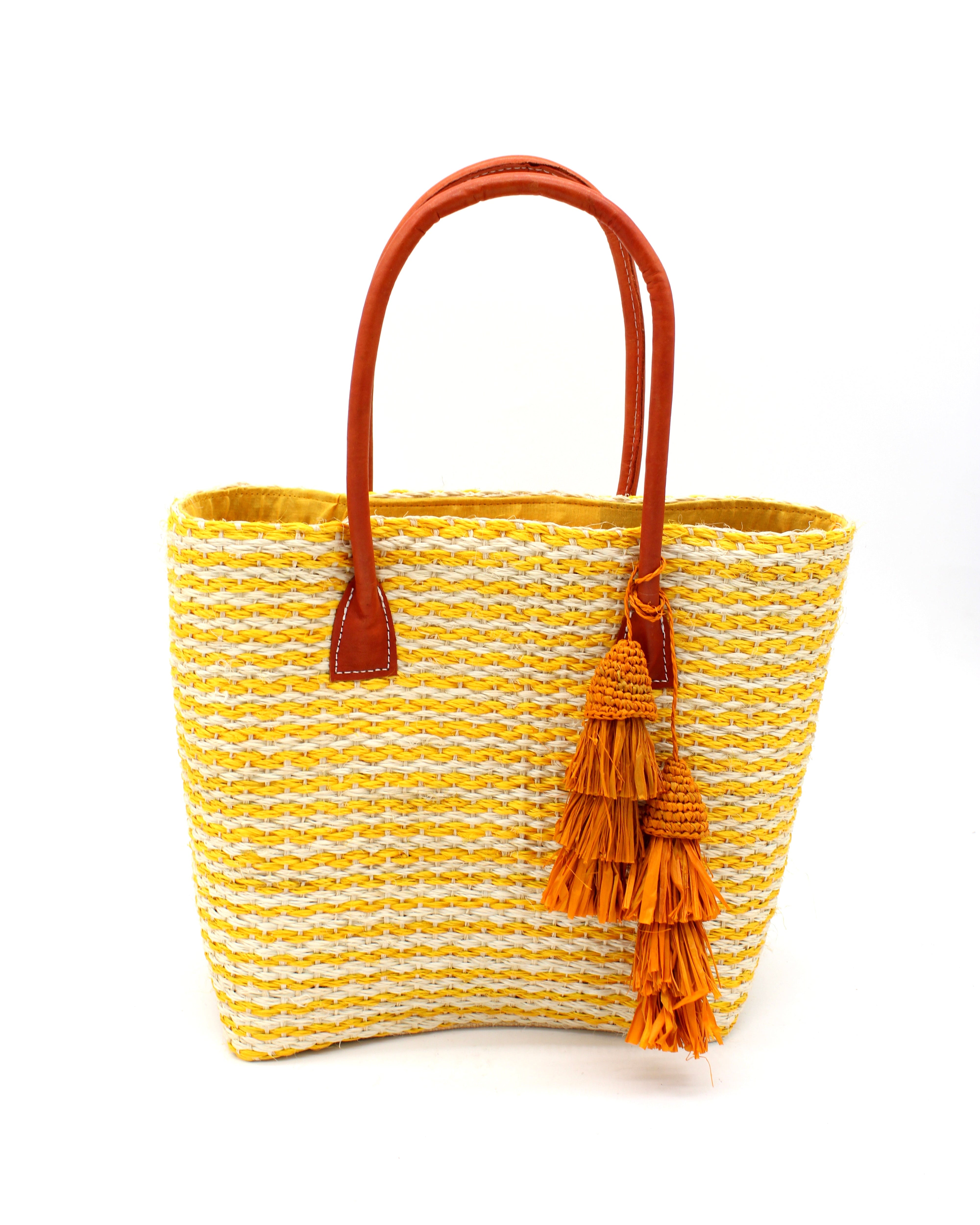 Cancun Small Sisal Basket Bag with Tassel Charm handmade natural sisal fibers woven into even width horizontal bands of saffron yellow and natural straw color that create a pinstripe pattern with matching knotted raffia tufts tassel charm embellishment and leather handles beach bag - Shebob