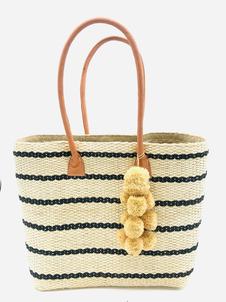 Capitola Black Two Tone Pinstripes Sisal Basket Bag with Waterfall Pompoms handmade woven natural sisal fiber tote bag in wide bancs of natural straw color with narrow bands of black in a horizontal stripe pattern with leather handles and matching waterfall pompom charm embellishment - Shebobo