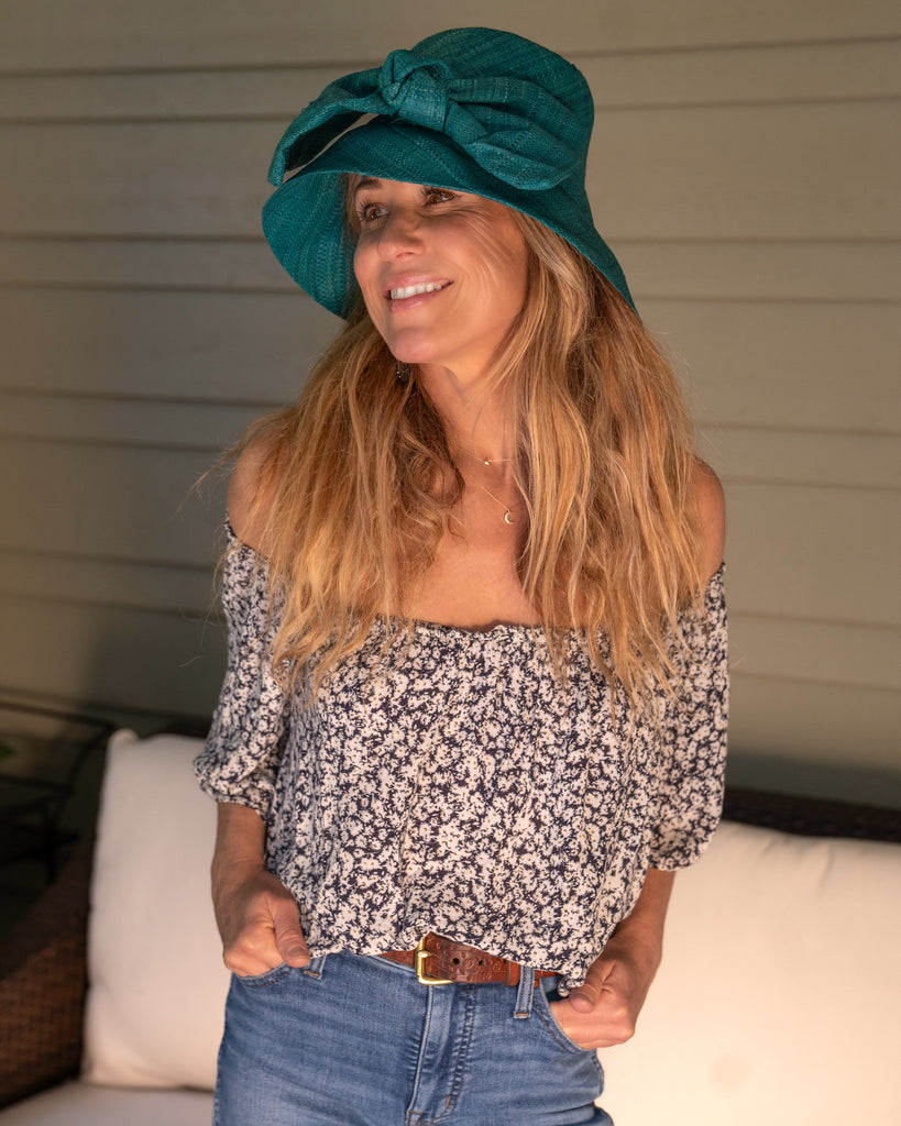 Model wearing Cara Teal big bow embellishment handmade loomed raffia in a solid hue of teal dark/blue/green straw bucket style cloche sun hat with matching oversized bow - Shebobo