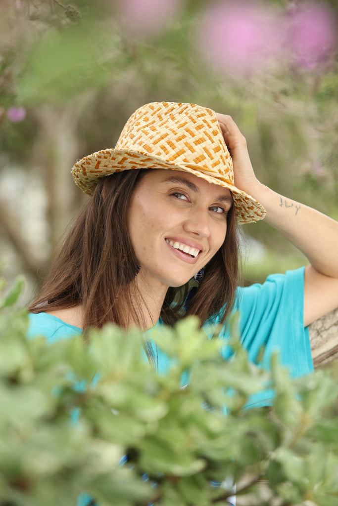 Model wearing Charlie Cinnamon Two Tone - Unisex Fedora Straw Hats handmade woven raffia palm fiber in a two tone crosshatch pattern of cinnamon/tobacco/brown and natural straw color pinched crown structured narrow brim with looped edging and matching raffia twist hat band - Shebobo