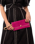 Model wearing ChiChi Fuchsia Straw Clutch Bag handmade loomed raffia palm fiber wristlet in fuchsia hot/bright/barbie/pink color with natural straw color cross stitch edging, button & loop closure, and braided wrist strap - Shebobo