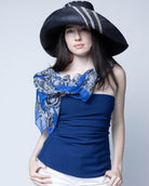 Model wearing Monica 5" & 7" Wide Brim Racing Stripe Packable Straw Sun Hats handmade loomed natural raffia palm fiber in a solid hue of black with a three stripe racing stripe pinstripe pattern of natural straw color that creates a swirl around the crown and brim of the hat lightweight breathable sun protection - Shebobo (with Cleo Snake Print Scarf Wrap)