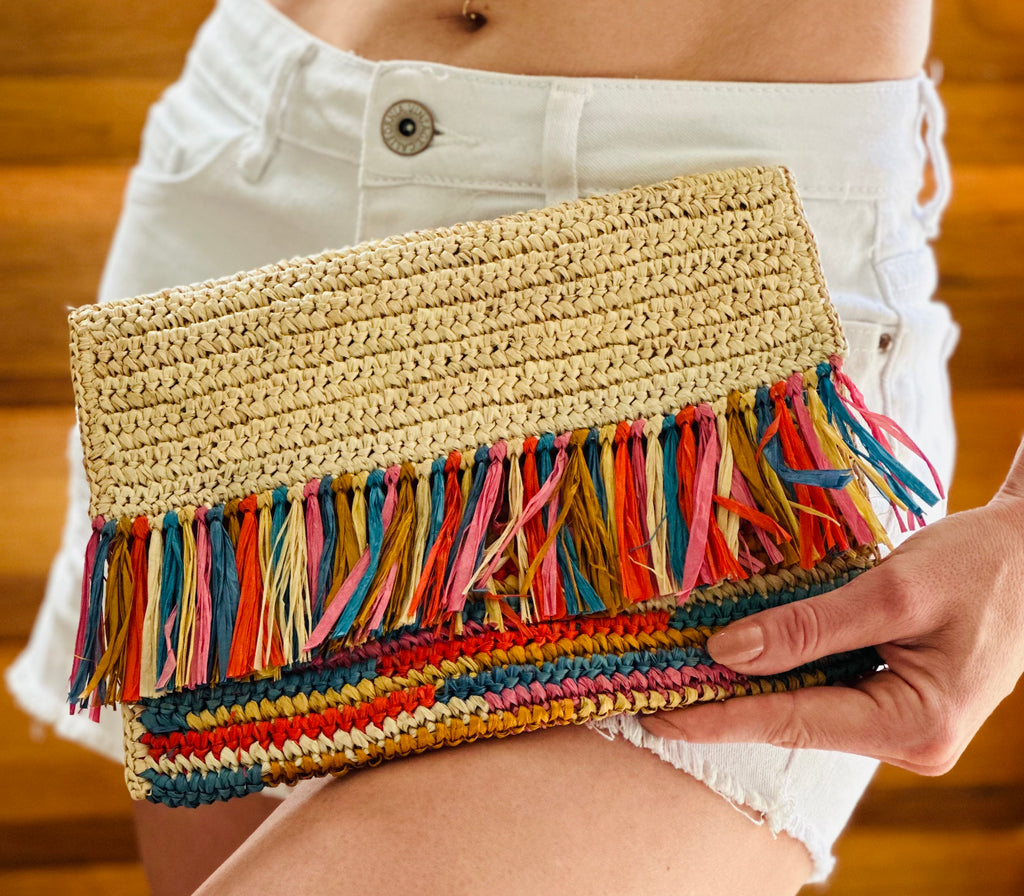 Model wearing Coco Fringe Crochet Straw Clutch Confetti Multicolor - orange yellow, pink, brown, and blue - and natural straw color two tone handmade purse with horizontal band of multicolor fringe - Shebobo