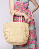 Model wearing Colette FlowerCrochet Straw Basket Handbag with Pockets handmade natural raffia palm fiber in a solid hue of natural straw color with geometric granny square floral cutout pattern on two large external pockets tote bag - Shebobo