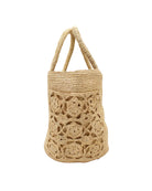 Detail view Colette FlowerCrochet Straw Basket Handbag with Pockets handmade natural raffia palm fiber in a solid hue of natural straw color with geometric granny square floral cutout pattern on two large external pockets tote bag - Shebobo