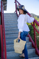 Model wearing ConCon crochet straw basket natural raffia straw color handbag textural bag - Shebobo (with 5" Brim Black Swirl Packable Straw Sun Hat)