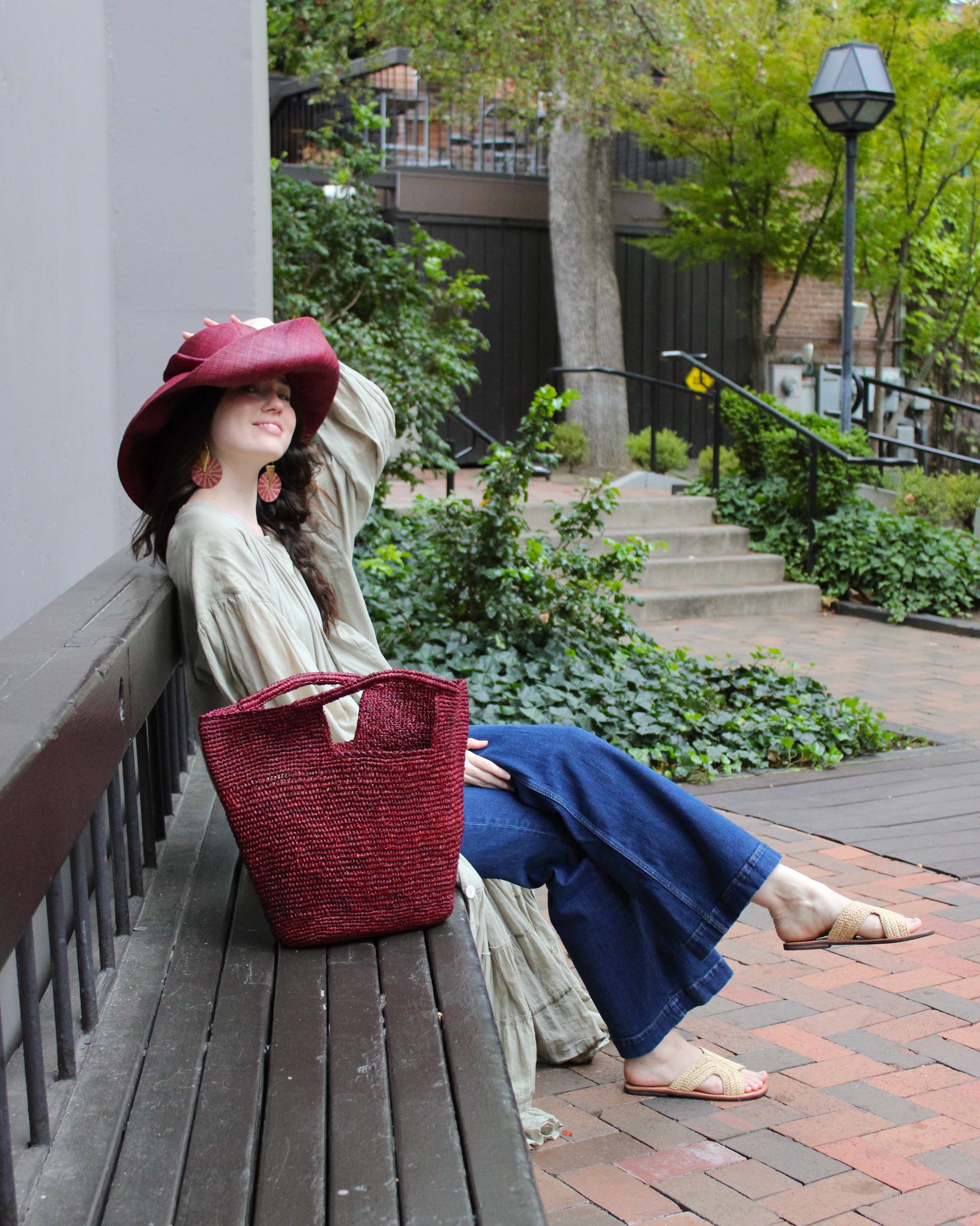 Model wearing ConCon Crochet Straw Basket handmade woven raffia palm fiber in a solid hue of umberwine bordeaux/claret/deep/dark/purple/red making a textured link pattern handbag tote - Shebobo (with Audrey 5" & 7" Wide Brim Big Bow Solid Color Packable Straw Sun Hats and Lizzie Crochet Straw & Leather Sandal Shoes)