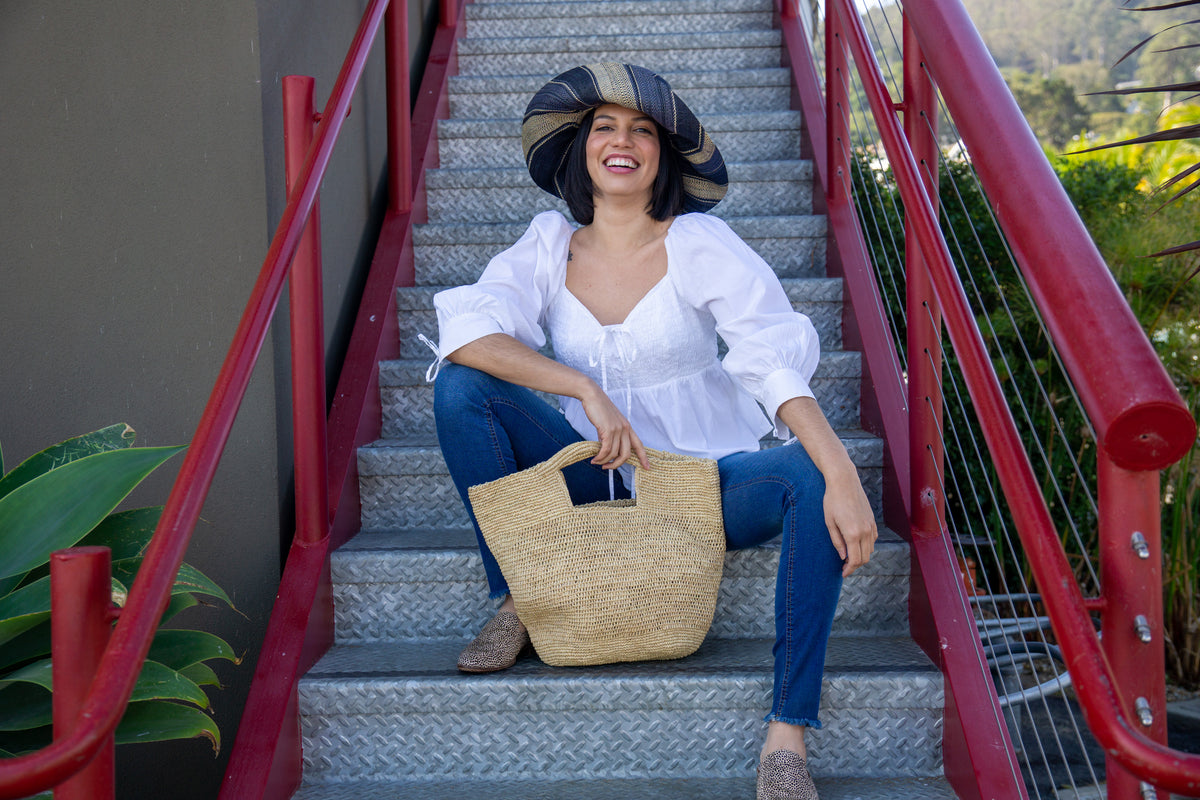 Model wearing ConCon crochet straw basket natural raffia straw color handbag textural bag - Shebobo (with 5" Brim Black Swirl Packable Straw Sun Hat)