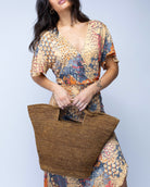 Model wearing ConCon Crochet Straw Basket handmade woven raffia palm fiber in a solid hue of cinnamon/tobacco/dark/brown making a textured link pattern handbag tote - Shebobo