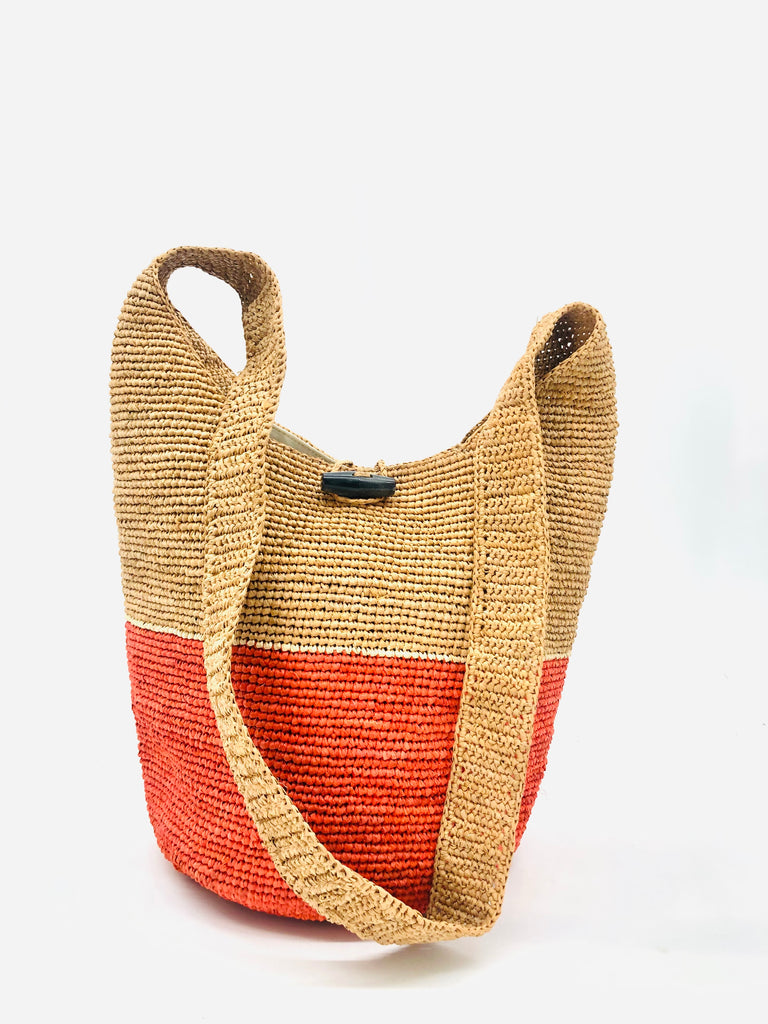 ConCon Two Tone Crochet Crossbody Bag handmade with interior liner, horn button and loop closure raffia purse coral orange bottom, with narrow natural straw color horizontal stripe separating light brown/tea colored top & shoulder strap - Shebobo