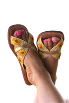 Model wearing Daisy Crochet Straw & Leather Sandal with Flower Embroidery & Metallic Detailing handmade crochet natural raffia palm fiber in a solid hue of natural straw color in two bands with saffron yellow petals and coral orange/red centered embroidered flower pattern wrap around the top  of the shoe with a band of metallic gold across the top summer sandals shoes - Shebobo