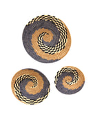 Dakarai Raffia Straw Wall Decor Display Basket Trays: Set of 3 handmade woven raffia palm fiber in a crochet loop technique creating a concentric swirl pattern of bands of  cinnamon/tobacco/brown, grey, and black and natural straw color checked pattern in a three tone spiral from the center to the outer edge set of three sized flat bowl trays - Shebobo