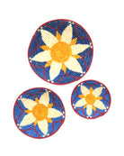Dakarai Raffia Straw Wall Decor Display Basket Tray: Set of 3 handmade woven natural raffia palm fiber in a crochet loop technique concentric coiled circular pattern with natural straw color, saffron orange/yellow, blue, and red centered star flower pattern set of three sized flat bowl trays - Shebobo