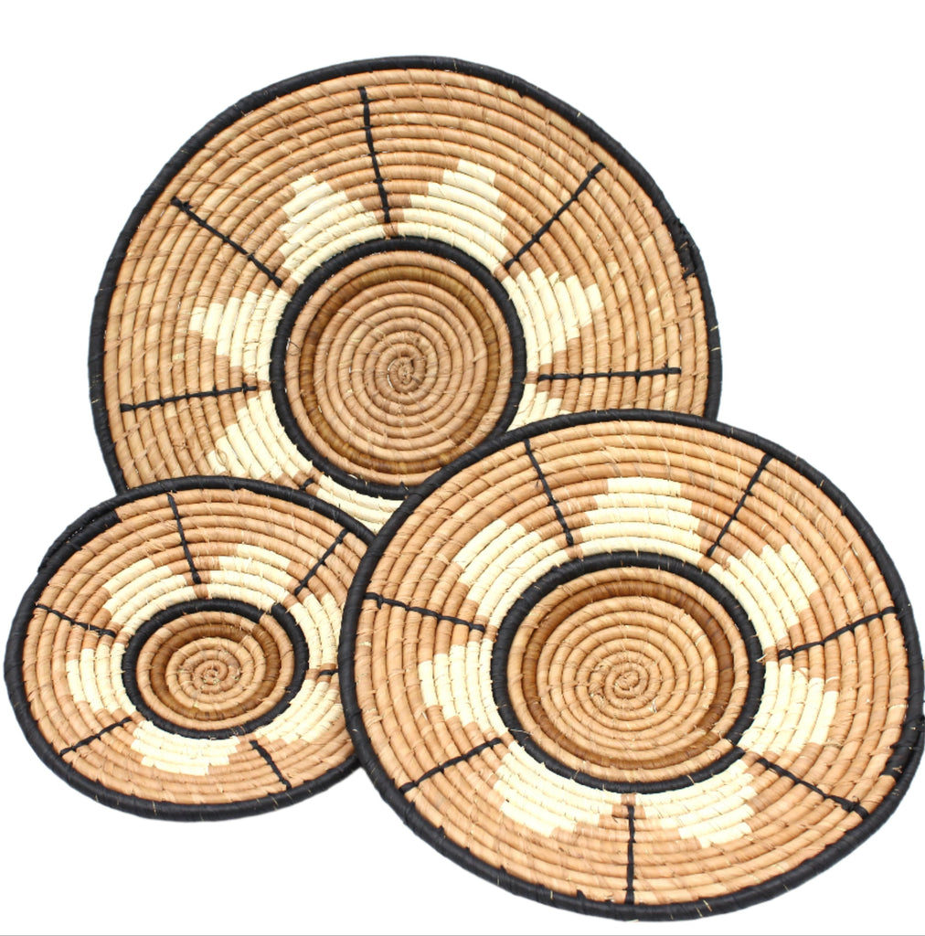 Dakarai Raffia Straw Wall Decor Display Basket Tray: Set of 3 handmade woven natural raffia palm fiber in a crochet loop technique concentric coiled circular pattern with natural straw color, cappuccino/tea/light/brown, cinnamon/tobacco/dark/brown, and black centered star flower pattern set of three sized flat bowl trays - Shebobo