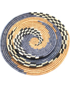 Detail view Dakarai Raffia Straw Wall Decor Display Basket Trays: Set of 3 handmade woven raffia palm fiber in a crochet loop technique creating a concentric swirl pattern of bands of  cinnamon/tobacco/brown, grey, and black and natural straw color checked pattern in a three tone spiral from the center to the outer edge set of three sized flat bowl trays - Shebobo