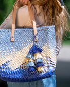 Model wearing Tassels Layered Raffia Tufts Charm Embellishment Denim Multi handmade knotted and brushed natural raffia palm fiber in a multicolor layered tuft tassel of denim light/retro/blue, natural straw color, and indigo dark/navy/blue beach bag handbag charm embellishment or party decor - Shebobo