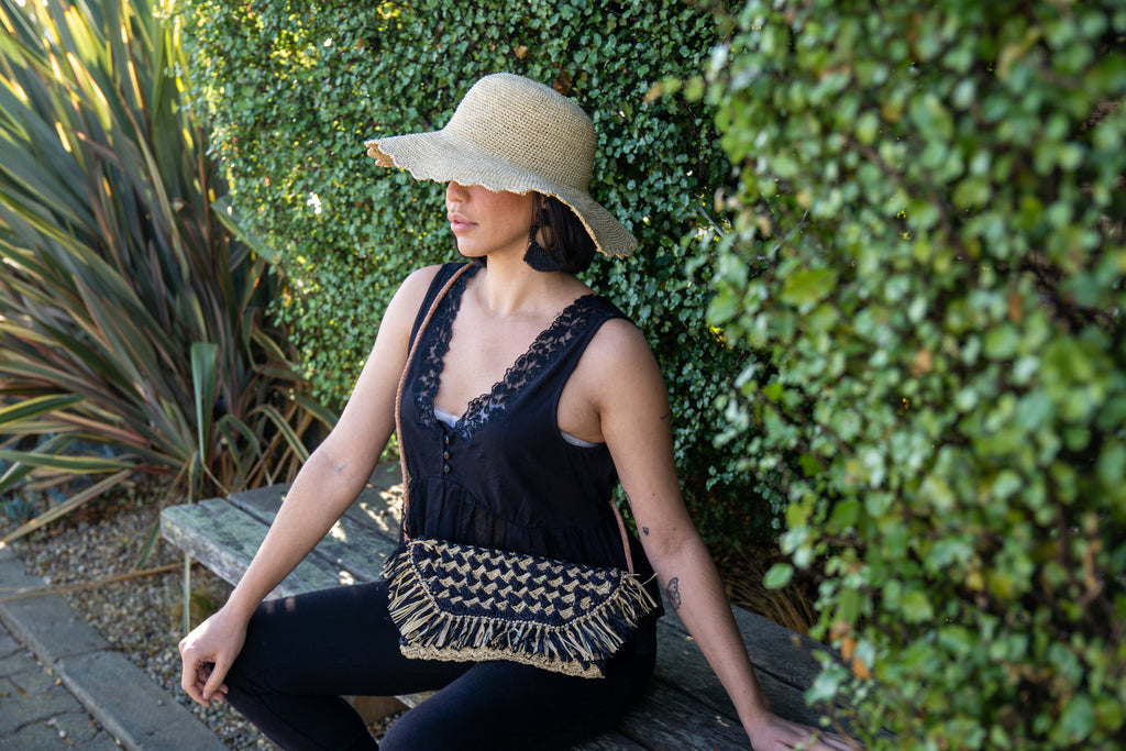 Model wearing Elsea black and natural two tone crossbody purse crochet raffia fringe edge braided leather shoulder strap bag - Shebobo
