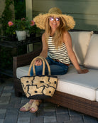 Model wearing Eva Embroidered Flower Crochet Straw Basket Handbag two tone handmade crochet raffia palm in a solid hue of black with natural straw color embroidered floral pattern and matching natural crochet handles beach bag tote purse - Shebobo (with Karin Macrame Straw Sun Hat)