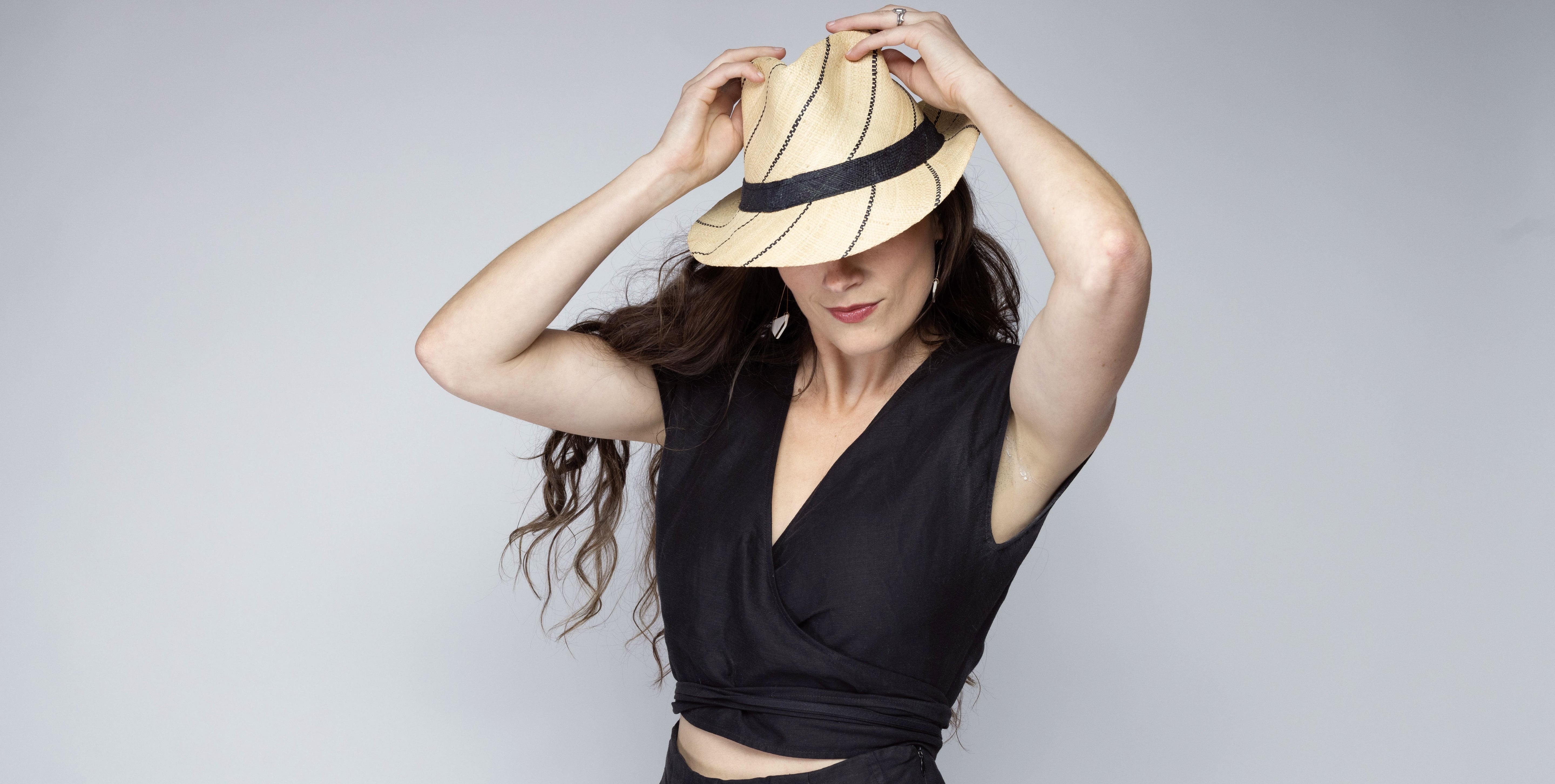 Model wearing Model wearing Fedra 2" Brim Fedora Unisex Straw Hats natural and black pinstripes packable raffia straw hat handmade loomed raffia in wide bands of natural straw color with black narrow bands create a stripe swirl pattern - Shebobo