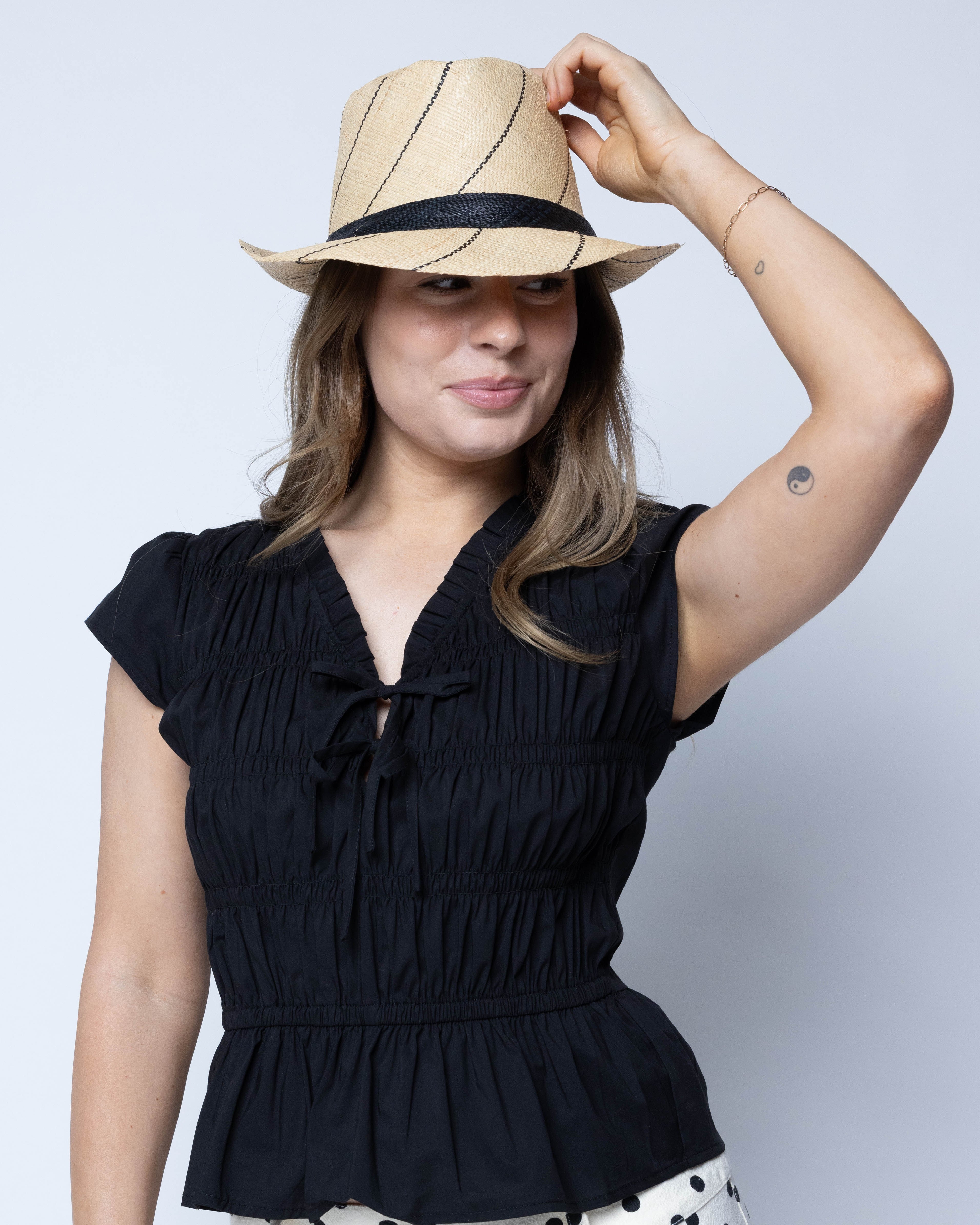Model wearing Fedra 2" Brim Fedora Unisex Straw Hats natural and black pinstripes packable raffia straw hat handmade loomed raffia in wide bands of natural straw color with black narrow bands create a stripe swirl pattern - Shebobo