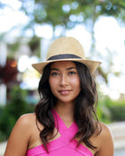 Model wearing Fedra Natural with Black Hat Band - Unisex Fedora Straw Hat handmade loomed natural raffia palm fiber in a solid hue of natural straw color with an attached black hat band - Shebobo