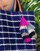 Model wearing Tassels Layered Raffia Tufts Charm Embellishment Fiesta Multicolor handmade knotted and brushed natural raffia palm fiber in a multicolor layered tuft tassel of fuchsia hot/bright/barbie/pink, natural straw color, grey, dark blue, black, and cappuccino light/brown beach bag handbag charm embellishment or party decor - Shebobo