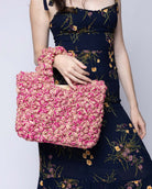 Model wearing Florence Fuchsia Pinks Multicolor Flower Crochet Straw Basket Handbag handmade natural raffia palm fiber in a multicolor hue combination of natural straw color, fuchsia hot/bright/pink, and light pink with subtle tied flower design consisting of 88 flowers crochet together along the outside of the bag as well as the handles purse tote - Shebobo