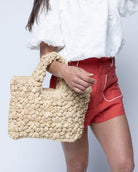 Model wearing Florence Flower Crochet Straw Basket Handbag handmade natural raffia palm fiber in a solid hue of natural straw color with subtle tied flower design consisting of 88 flowers crochet together along the outside of the bag as well as the handles purse tote - Shebobo