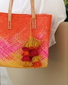 Model wearing Tassels Layered Raffia Tufts Charm Embellishment Fuchsia Multi handmade knotted and brushed natural raffia palm fiber in a multicolor layered tuft tassel of fuchsia hot/bright/barbie/pink, coral orange/red, and saffron orange/yellow beach bag handbag charm embellishment or party decor - Shebobo