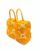 Side view Gemma Crochet Disc Rectangle Saffron and Butter Straw Basket Handbag handmade woven raffia palm fiber in a two tone multicolor pattern of saffron yellow/orange and butter light yellow create a coiled braid disc pattern result in a star pattern around the bag with matching woven handles top handle bag - Shebobo