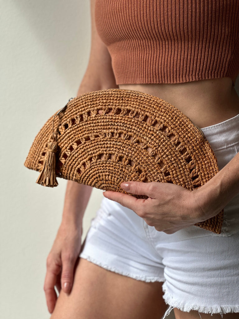 Model wearing Half Moon XL Blush Crochet Straw Clutch with Tassel Zipper Pull handmade with weave creating varying half circle bands of texture - Shebobo