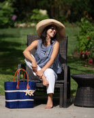 Model wearing Havana Sisal Basket Bag with Tassel Charm Embellishment handmade sisal fiber woven into horizontal wide bands of dusk dark blue with two evenly spaced narrow bands of natural straw color create a stripe pattern with natural crochet starfish charm embellishment and leather handles handbag shoulder bag - Shebobo (with 7" Wide Brim Packable Straw Sun Hat)