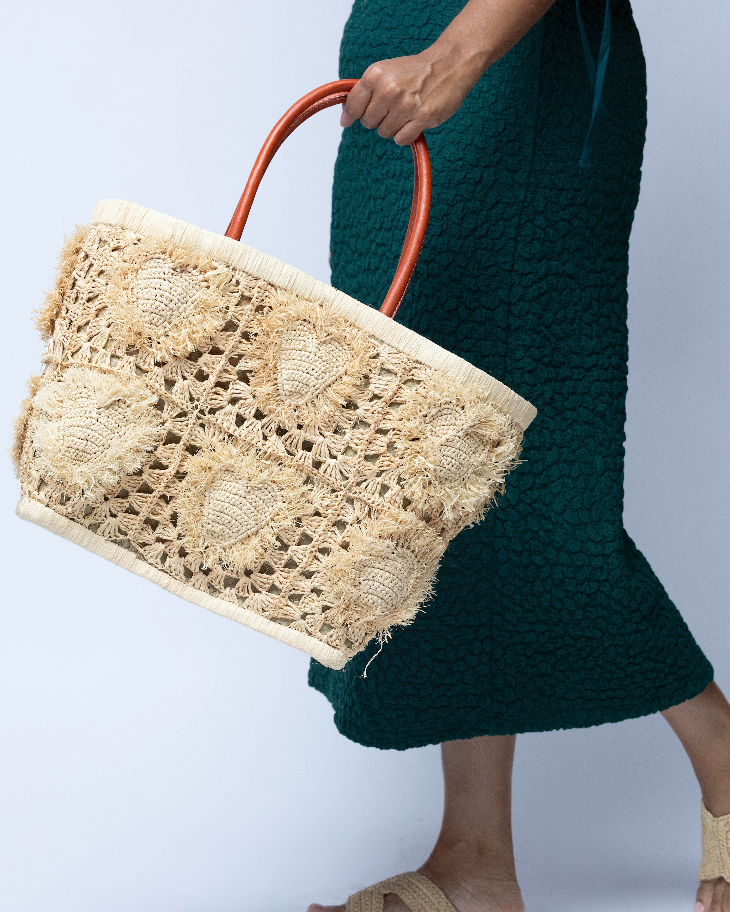 Model wearing Hearts Crochet Straw Basket Bag with Fringed Heart Pattern handmade woven raffia in a solid hue of natural straw color with granny square pattern and raised/stuffed heart pattern with fringe edges on each heart, looped base and top binding, as well as leather handles purse beach bag shoulder bag - Shebobo 