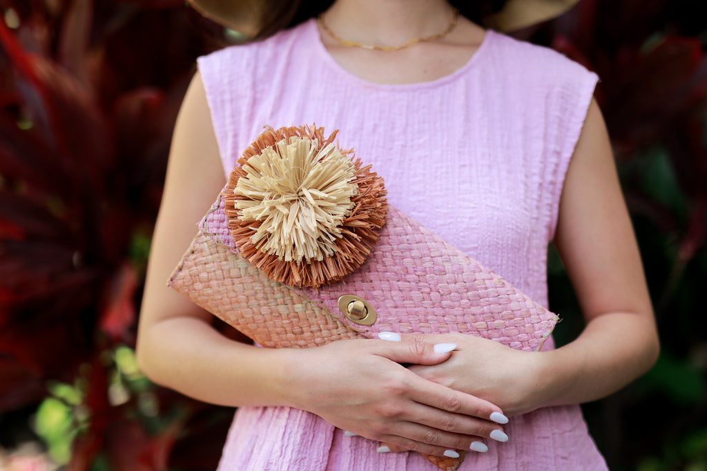 Model wearing Holden Ombre Blush Straw Clutch with Flower Pouf handmade woven raffia dip dyed gradient of lavender purple/pink, natural, and blush orange/pink with large blush and natural fringe flower embellishment - Shebobo