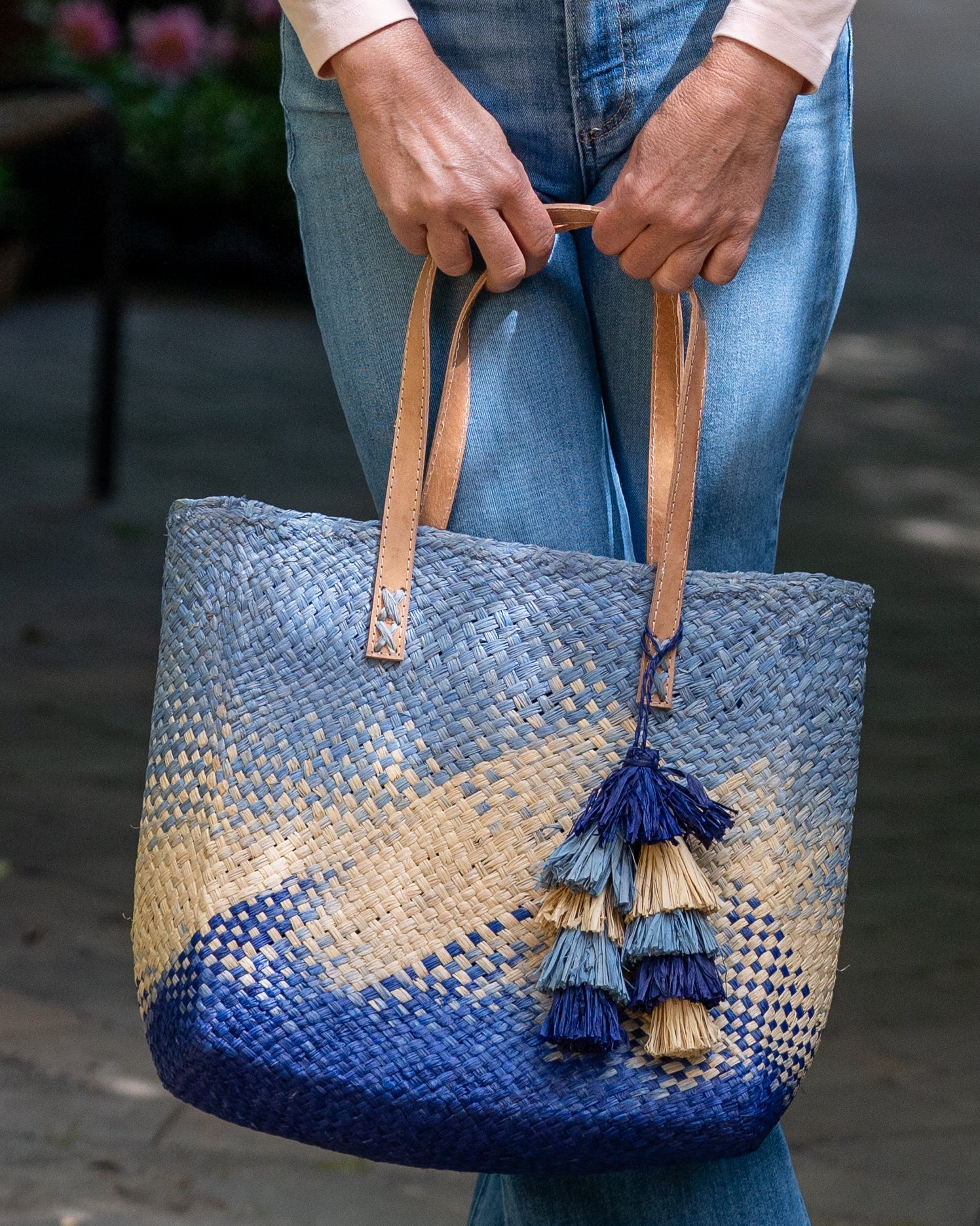 Model wearing Holden Ombre Denim Straw Handbag Tassel Charm Embellishment handmade woven raffia dip dyed gradient of denim retro/light/blue, natural straw color, and dusk navy/dark/blue with matching multicolored, multi-tiered raffia tuft tassel - Shebobo