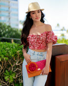 Model wearing Holden Ombre Fuchsia Straw Clutch with Flower Pouf handmade woven raffia dip dyed gradient of fuchsia bright/barbie/pink, saffron yellow, and coral orange/red with large coral and fuchsia fringe flower embellishment - Shebobo (with Charlie Natural Unisex Fedora Straw Hat)