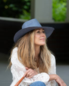 Model wearing Jamie Panama 3" brim handmade loomed raffia in a solid hue of denim retro/light/blue with attached matching hat band uv/sun protection lightweight breathable straw sun hat - Shebobo