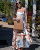 Model wearing JoJo Woven Straw Handbag with Metal Ring Handle handmade natural raffia palm fiber in a solid hue of Cappuccino tea/light/brown with matching woven thread texture and metallic circular metal ring handle - Shebobo