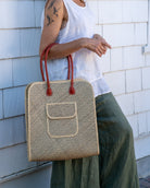 Model wearing Josephine 50's Inspired Woven Straw Handbag handmade natural raffia palm fiber in natural straw color woven with contrasting Grey thread stitching in a subtle diagonal stripe pattern consisting of bands of ovals and circles with loomed raffia edging around the bag as well as the pocket and flap of the exterior pocket - Shebobo