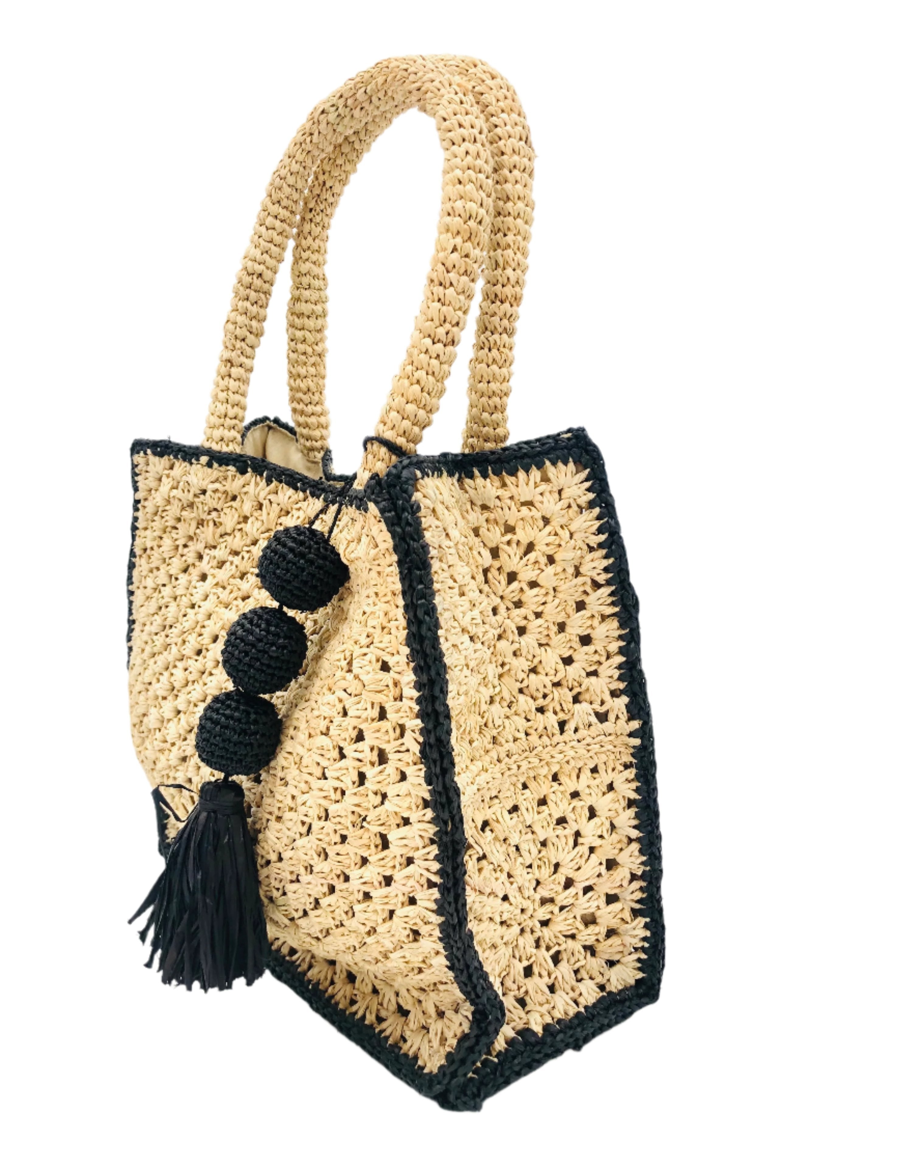 Side view Kimba handmade crochet two tone handbag purse natural straw color with black trim and crochet cascading balls plus tassel bag charm embellishment - Shebobo