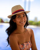 Model wearing Kelly Crochet Fedora - Unisex Straw Sun Hats handmade woven natural raffia palm fiber in a solid hue of natural straw color with woven in multicolored hatband of fuchsia bright/hot/barbie/pink, coral orange/red, and navy blue hues - Shebobo