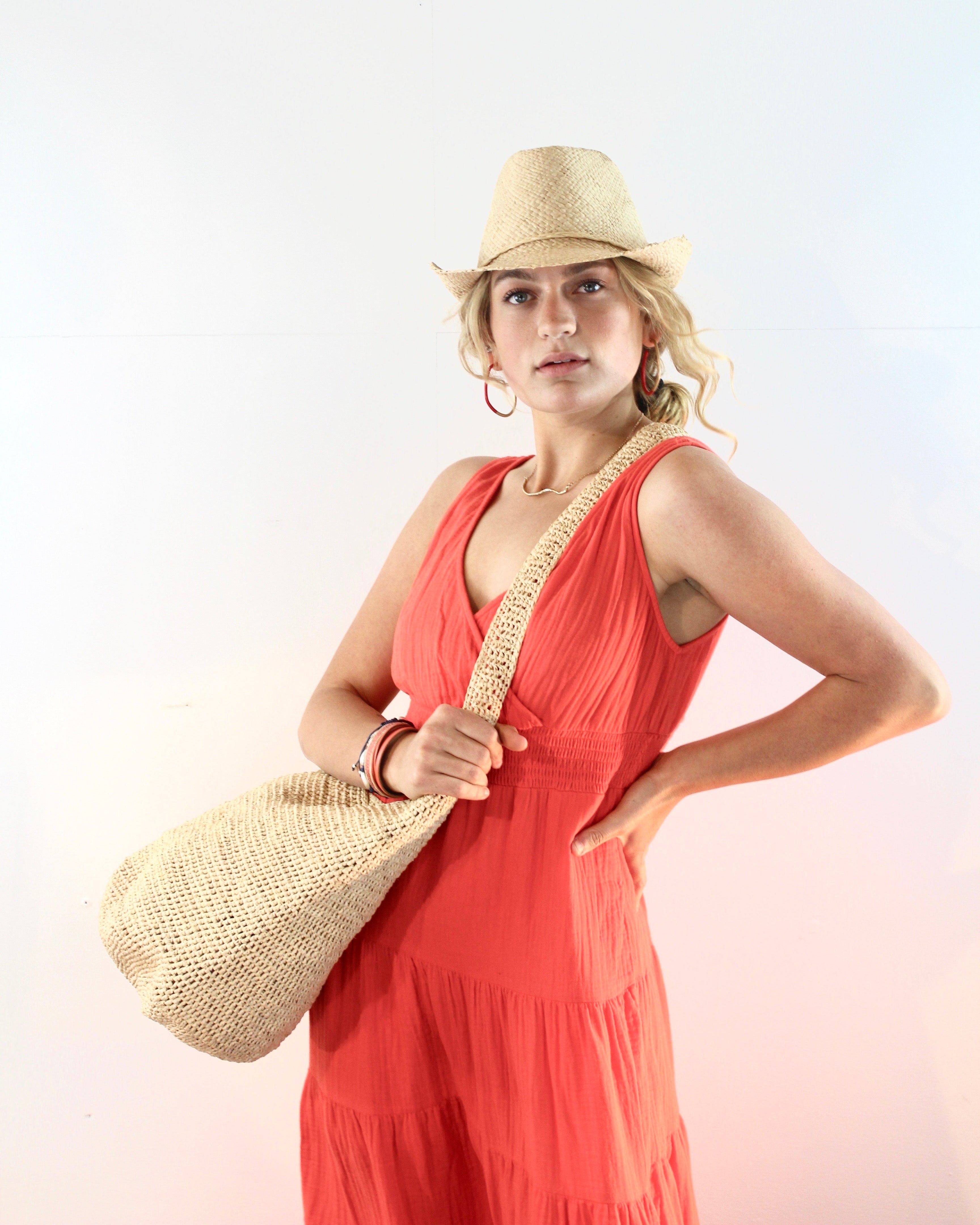 Model wearing Kiki Crochet Straw Crossbody Bag handmade natural raffia palm fiber in a crochet pattern of subtle linked bands in a solid hue of natural straw color purse - Shebobo
