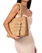 Model wearing Kimba Crochet Handbag with Sphere Tassel Charm Embellishment handmade natural raffia palm fibers crochet into a granny square pattern with cappuccino/light brown detail edging - Shebobo