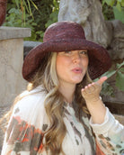 Model wearing Leor Mocha crochet straw hat handmade woven natural raffia palm fiber in a solid hue of mocha chocolate/dark/brown raffia 3" brim packable straw hat with matching adjustable braided hat band - Shebobo