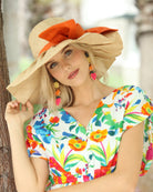Model wearing Lilly 5" Brim Fan Straw Sun Hat with Big Coral orange/red bow and matching hatband on handmade natural loomed raffia pleated wide brim hat - Shebobo