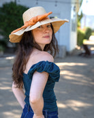 Model wearing Lilly 5" Brim Fan Straw Sun Hat with Big Peaches light/orange bow and matching hatband on handmade natural loomed raffia pleated wide brim hat - Shebobo