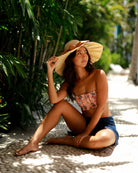 Model wearing Lilly 5" Brim Fan Straw Sun Hat with Big Blush orange/pink bow and matching hatband on handmade natural loomed raffia pleated wide brim hat - Shebobo