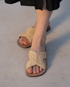 Model wearing Lizzie Crochet Straw & Leather Sandal handmade crochet natural raffia palm fiber in a solid hue of natural straw color in a h-shape double band across the top of the shoe and leather soles summer slide shoe - Shebobo