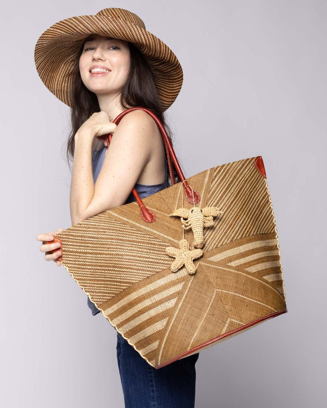 Model wearing Lobster & Starfish Tie Crochet Raffia Charm Embellishment handmade natural raffia palm fiber is crochet into 3D coastal lobster and starfish shapes in natural straw color and connected with raffia twist tie beach bag embellishment - Shebobo