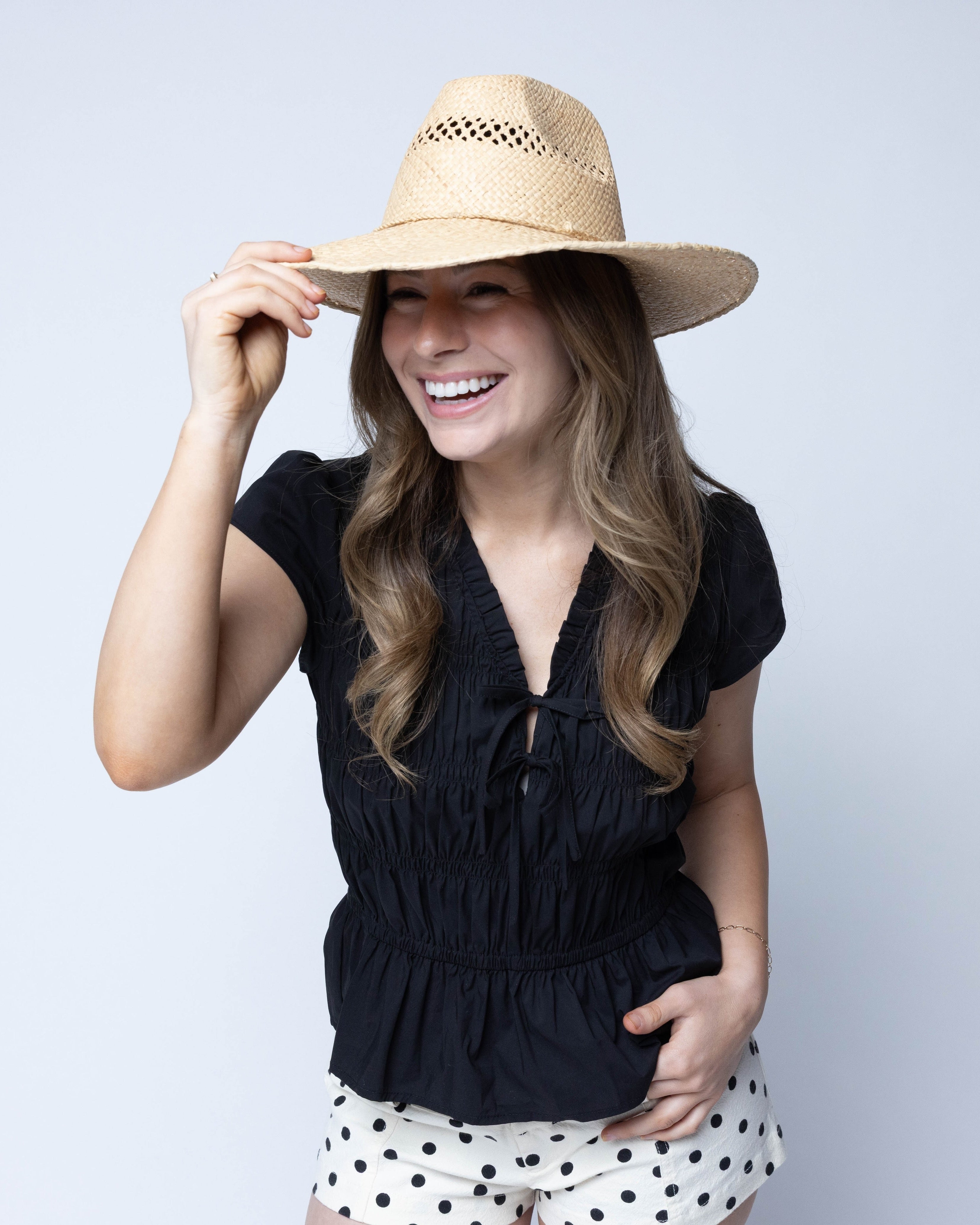 Model wearing Macho Natural Unisex Straw Cowboy Hat with Adjustable Wire Rim handmade woven raffia in a solid hue of natural straw color in a structured crown style with open weave pattern for breathability and pliable wire rim with matching twisted cord hat band - Shebobo
